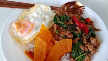 Tayland yemekleri kızarmış domuz baharatı ve fesleğenli pilav ve kızarmış yumurta ve körili Benincasa Hispida beyaz tabağı.