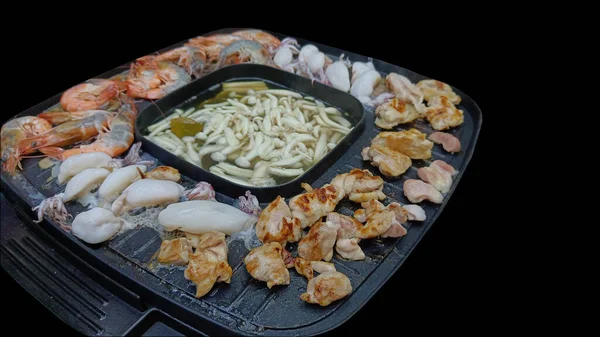 Cook on the electric grill, beef, pork, chicken, shrimp, squid and mushroom broth on a black background
