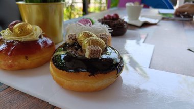 Çikolata kaplı, çilekli ve beyaz tabakta paskalya yumurtalarıyla süslenmiş renkli çörekler.