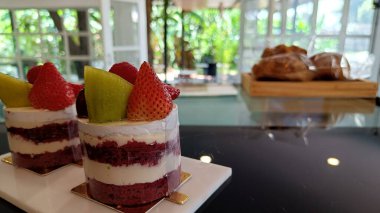 Taze çilekle süslenmiş kırmızı kadife pasta ve beyaz tabakta meyve..