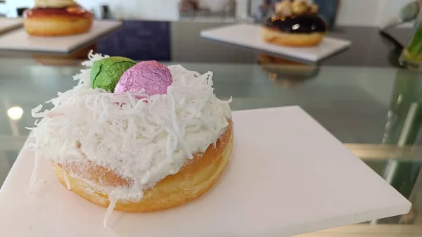 Donut kaplı hindistan cevizi ve beyaz tabakta pembe ve yeşil paskalya yumurtalarıyla süslenmiş.