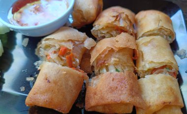 Kızarmış börekler siyah tabak Tayland yemeği menüsünde dilimlenmiş.