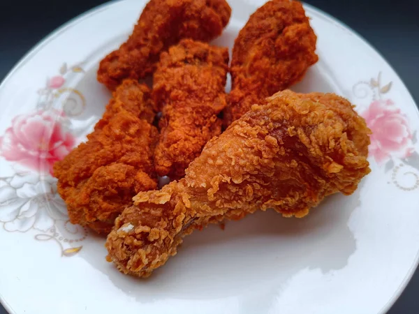 Tabakta kızarmış tavuk kanadı, siyah arka planda.