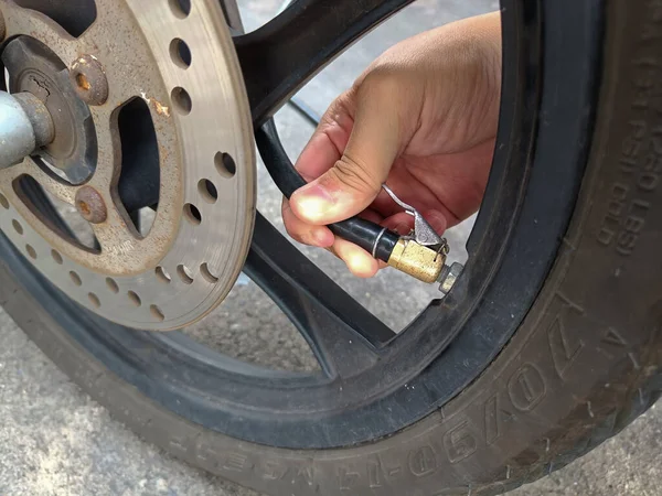 Asian man inflates old motorcycle wheels for road safety