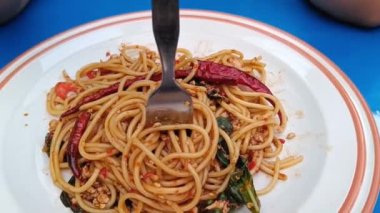 Asian woman using a fork to scoop Spicy spaghetti pork. Drunken Spaghetti Thai call Popular in street food
