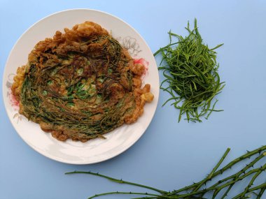 Thai call Kai Jeow Cha Om or omelette with acacia leaves on blue background
