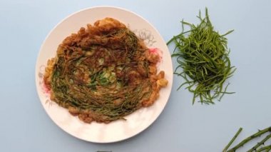 Thai call Kai Jeow Cha Om or omelette with acacia leaves on blue background