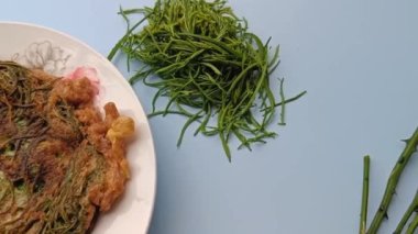 Thai call Kai Jeow Cha Om or omelette with acacia leaves on blue background