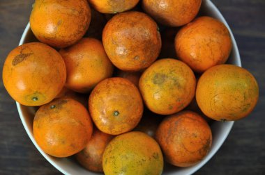 Olgun mandalina, mandalina, portakallar bir kasede, ahşap bir masada.