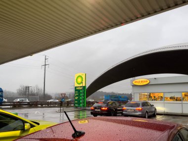 İsviçre 'deki İngiliz petrol istasyonunda bir kafenin yanına birkaç araba park edilmiş.