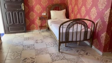 Odanın kapısı açık bir otel odasında tek kişilik yatak.