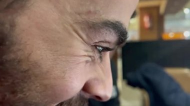 Kafeteryada dizüstü bilgisayarını kullanan genç bir adamın yakın çekim görüntüsü.