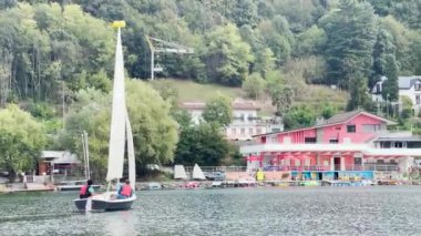 İtalya 'da Parco Naturale dei Laghi gölünde bir teknede iki kişi yelken açıyor.