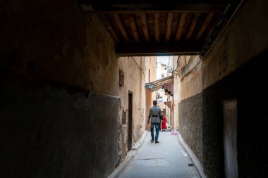 Fes 'in eski Medine' sinde insan dar bir sokakta yürüyor.
