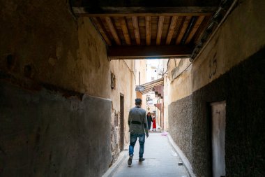Fes 'in eski Medine' sinde insan dar bir sokakta yürüyor.