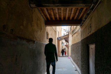 Fes 'in eski Medine' sinde insan dar bir sokakta yürüyor.