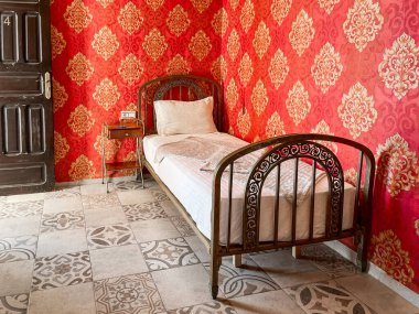 Otel odasında beyaz çarşaflı tek kişilik yatak.