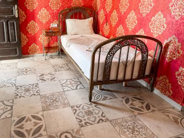 Otel odasında beyaz çarşaflı tek kişilik yatak.