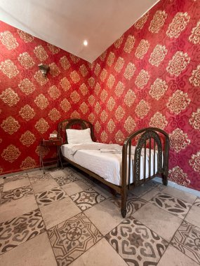 Otel odasında beyaz çarşaflı tek kişilik yatak.