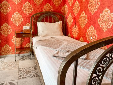 Otel odasında beyaz çarşaflı tek kişilik yatak.