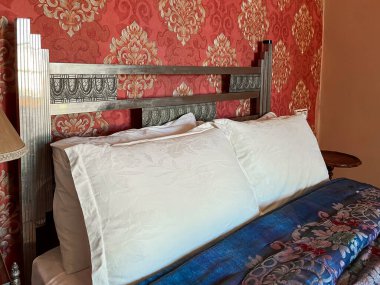 Beyaz yastıklı çift kişilik yatak ve otel odasında kırmızı bir duvar.