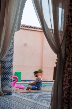 Kafkasyalı bir adam otelin havuz kenarında dinleniyor.