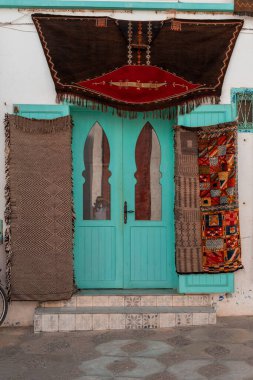 Asilah 'taki halı dükkanının kapısında el yapımı halılar asılı.
