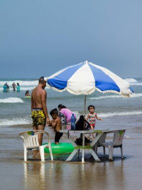 Sahilde oynayan çocukları izleyen bir adam.