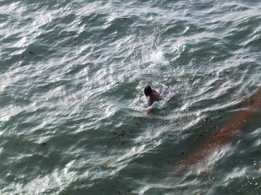Genç adam okyanusta tek başına yüzüyor.