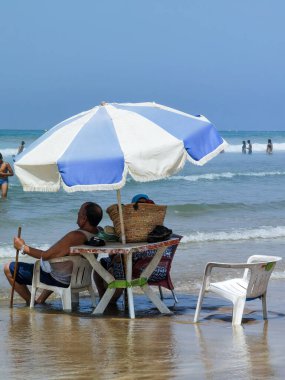Koca ve karısı yaz tatili boyunca okyanus suyunda sandalyelerinde dinleniyorlar.