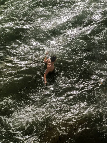 Genç adam okyanusta tek başına yüzüyor.