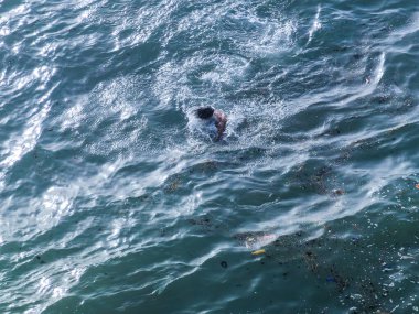 Genç adam okyanusta tek başına yüzüyor.