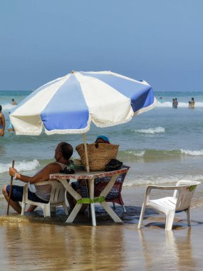 Koca ve karısı yaz tatili boyunca okyanus suyunda sandalyelerinde dinleniyorlar.