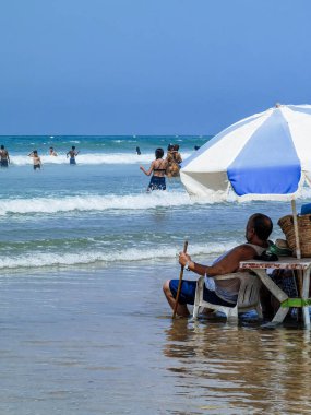 Koca ve karısı yaz tatili boyunca okyanus suyunda sandalyelerinde dinleniyorlar.