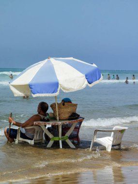 Koca ve karısı yaz tatili boyunca okyanus suyunda sandalyelerinde dinleniyorlar.