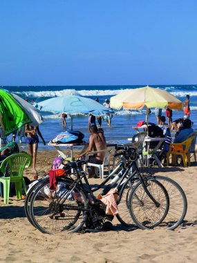 Birkaç bisiklet kalabalık bir plaj ve birkaç şemsiye.