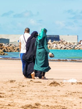 Müslüman bir aile sahilde birlikte yürüyor.