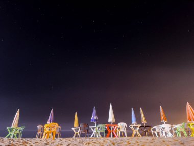 Geceleri sahilde sandalyeli bir sürü şemsiye.