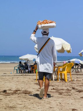 Fas sahilinde tatlı çörek satan bir adam.