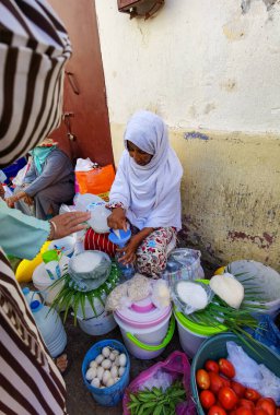 Faslı bir kadın müşterisine satmak için plastik bir şişeye süt döküyor.