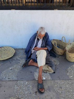 Yaşlı Faslı adam Fas 'ta el yapımı hasır şapka satıyor.