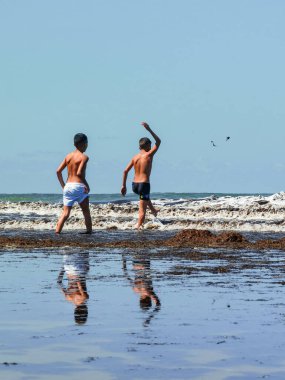 Fas sahilinde birlikte oynayan iki genç çocuk.