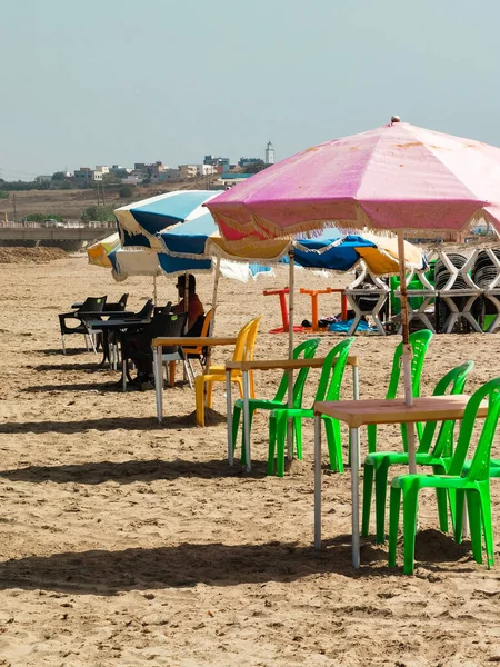 Fas sahilinde birkaç masa ve şemsiyeli sandalye.