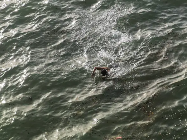 Genç adam okyanusta tek başına yüzüyor.