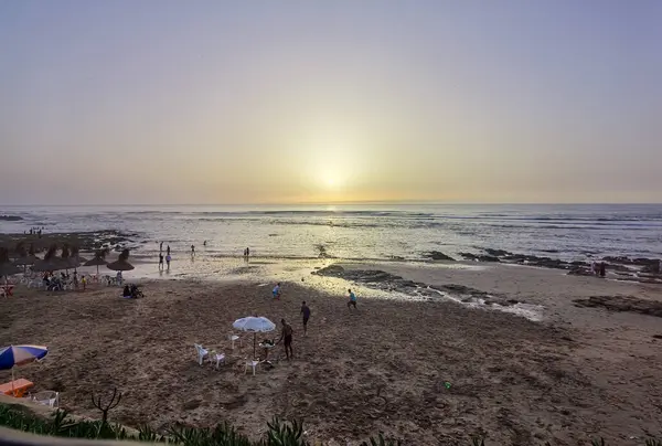 Gün batımında plajda futbol oynayan bir grup arkadaş.