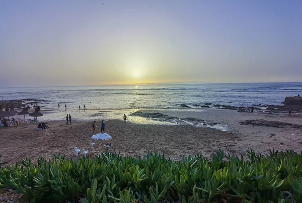 Gün batımında plajda futbol oynayan bir grup arkadaş.