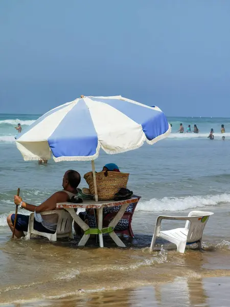 Koca ve karısı yaz tatili boyunca okyanus suyunda sandalyelerinde dinleniyorlar.