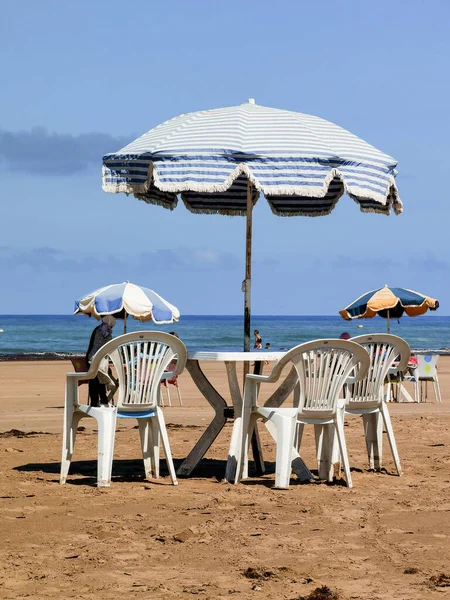 Fas sahilinde sandalyeli ve şemsiyeli bir masa, Asilah.