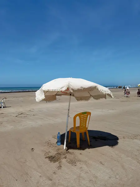 Fas sahilinde bir sandalye ve bir şemsiye, Asilah.