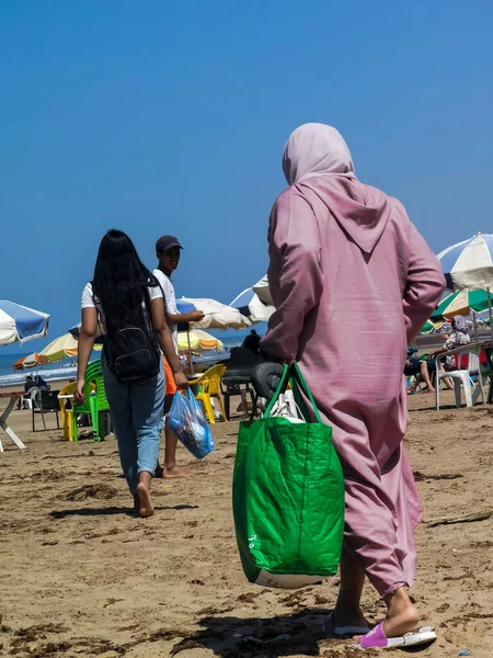 Sahilde yürüyen Faslı kadın.